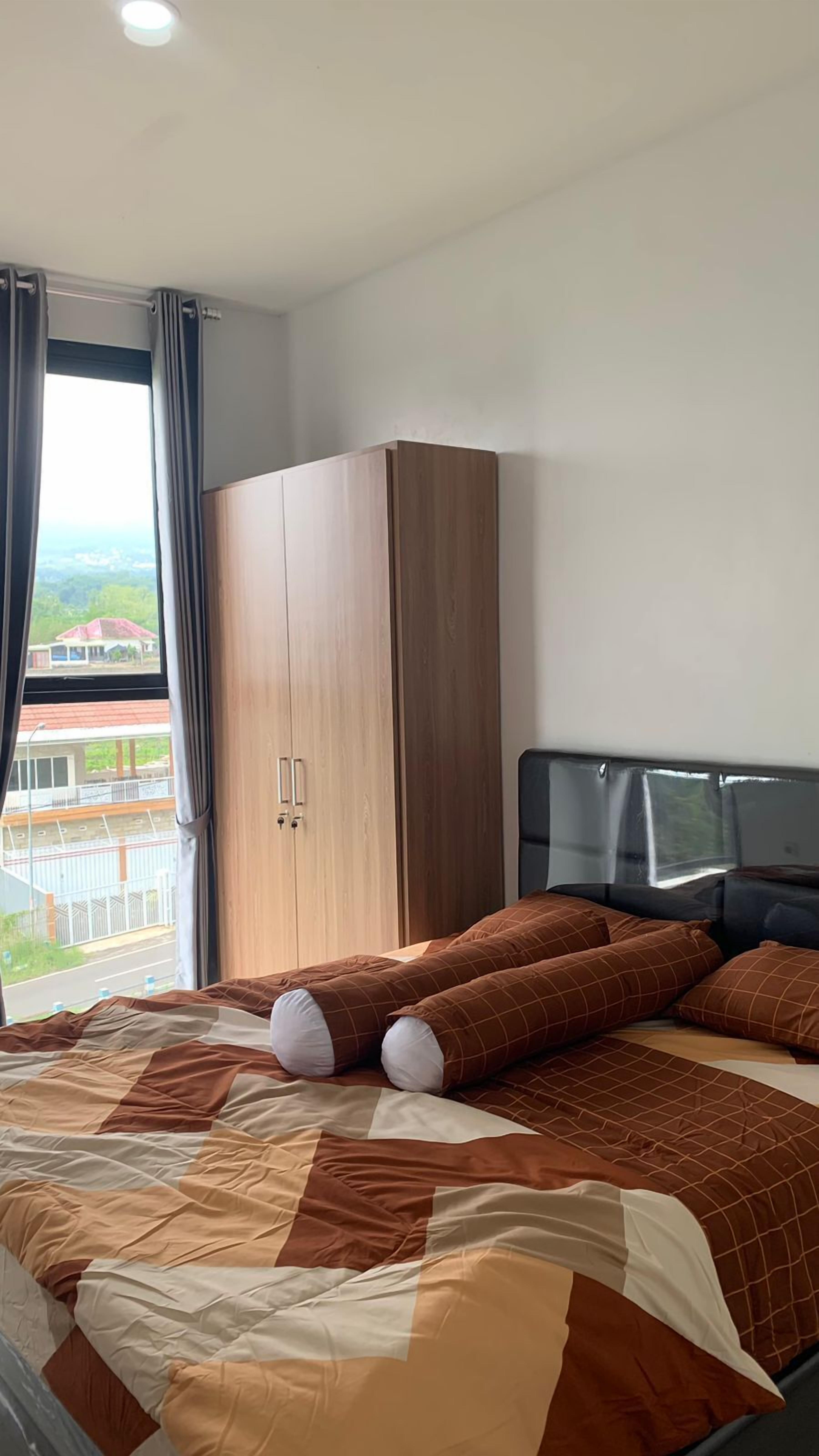 A bedroom with a large bed, a wardrobe, and a view of the outside.