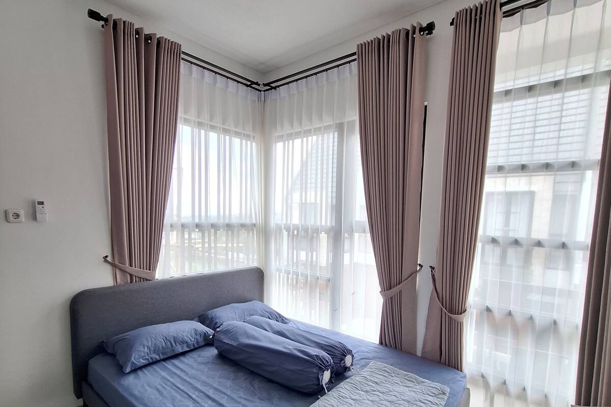 A bedroom with a bed, curtains, and a window.