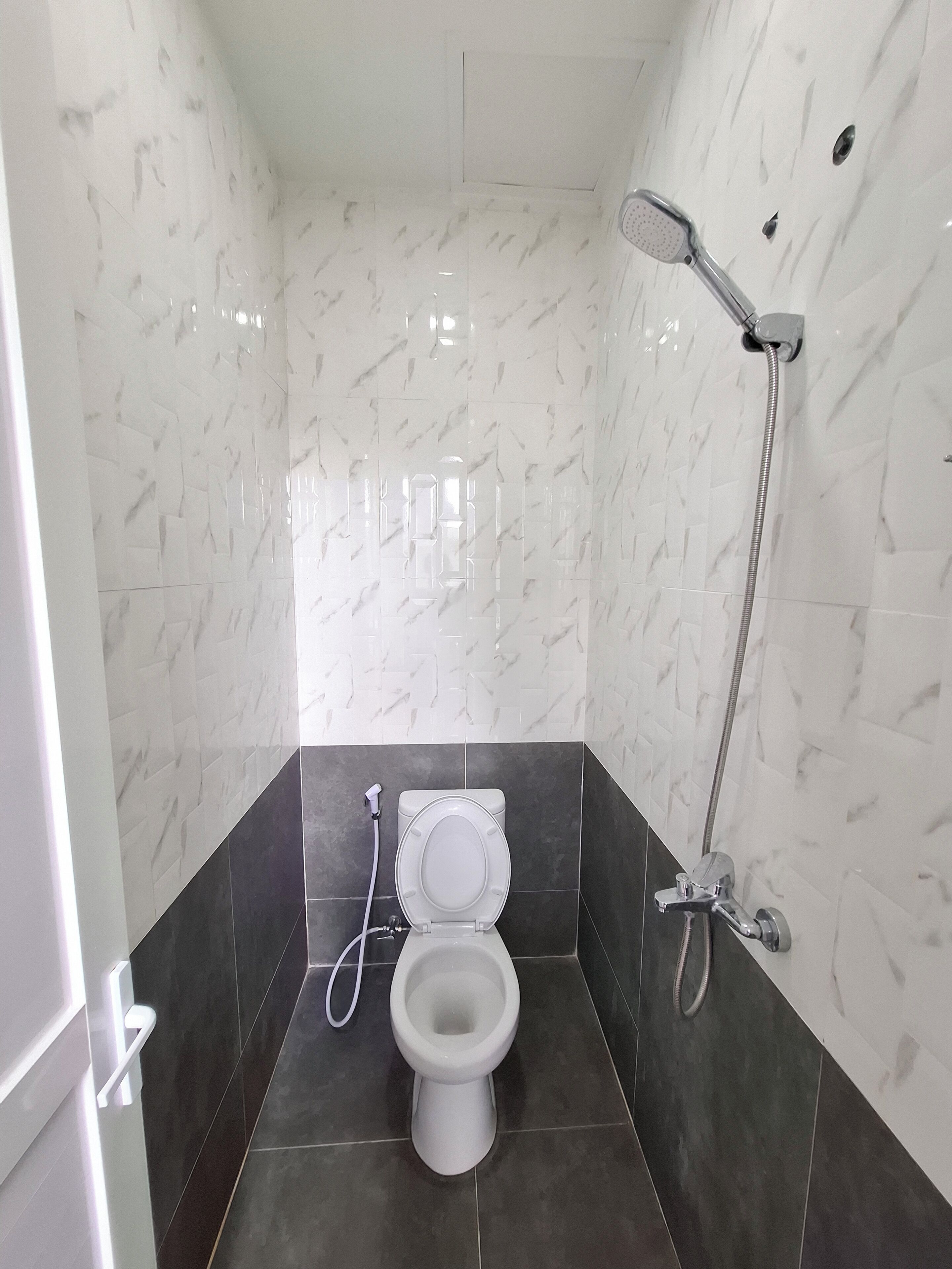 A small, modern bathroom with a toilet, a shower, and a mirror.