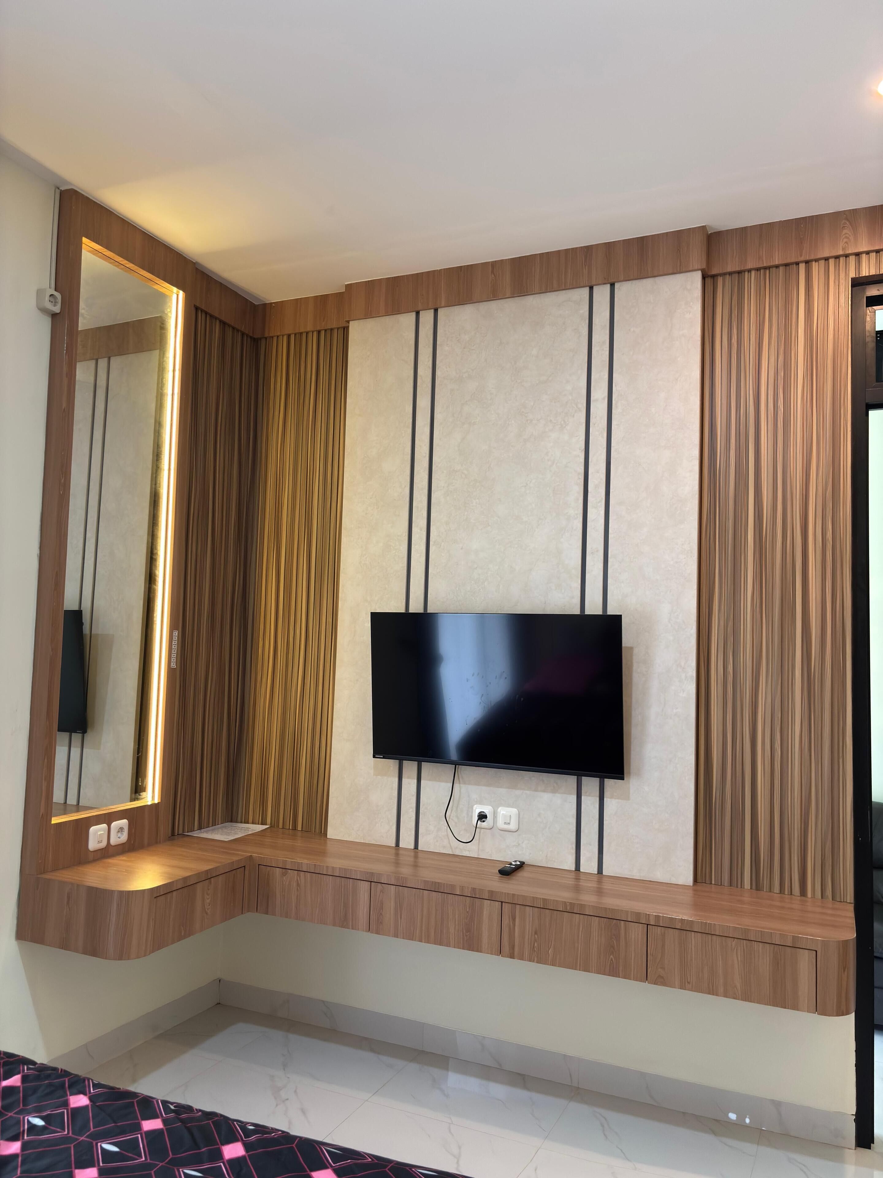Un soggiorno moderno con una grande televisione a schermo piatto fissata a un pannello di legno.