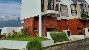 A modern residential building with a sloped roof, large windows, and a well-maintained garden area. - Athara Residence (Batu)