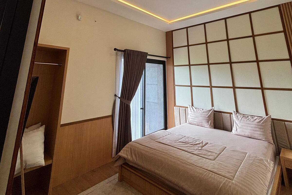 A modern bedroom with a bed, a wardrobe, a window with curtains, and a ceiling with recessed lighting.