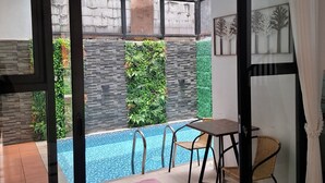 A modern indoor pool area with a glass door leading to a garden. - Athara Residence (Batu)