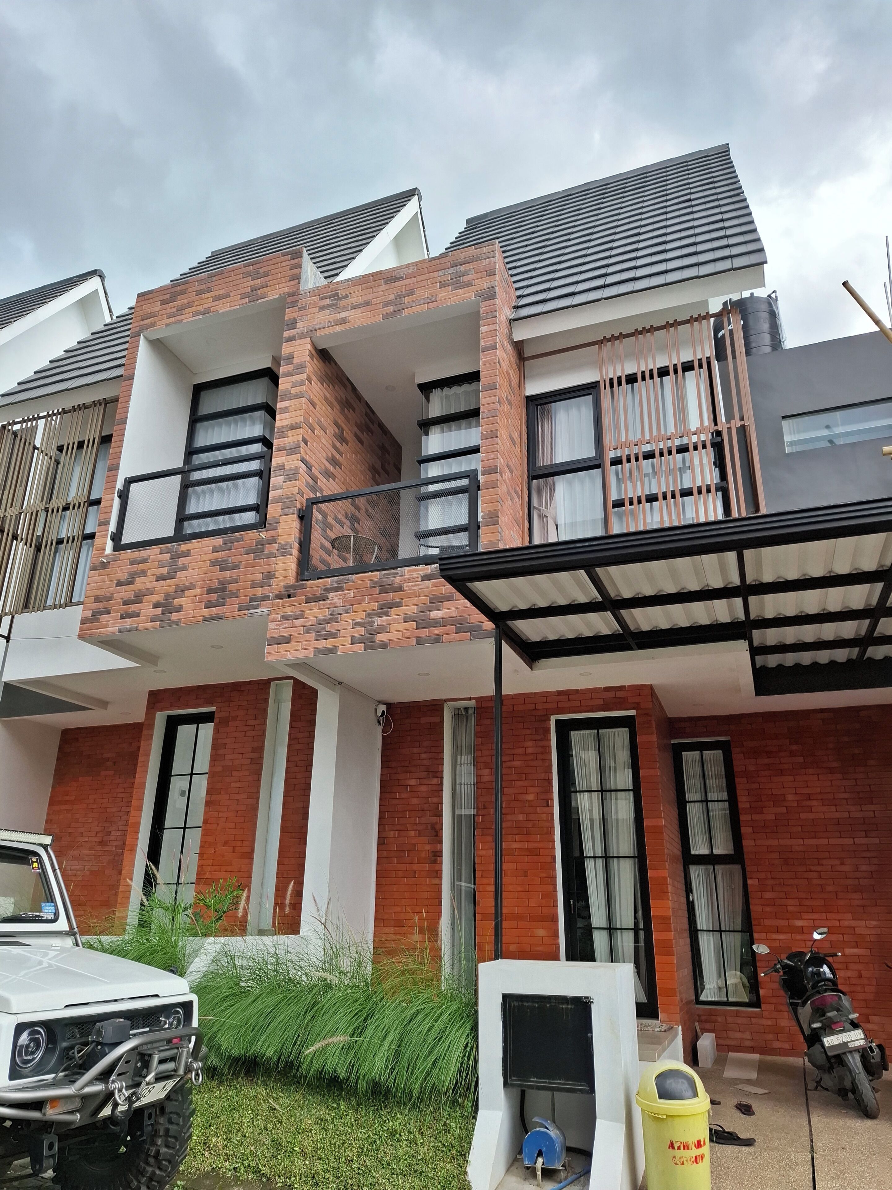 A modern two-story house with a balcony, a parked car, and a motorcycle.