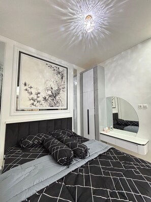 A bedroom with a bed, a large framed artwork, a mirror, and a ceiling light fixture.