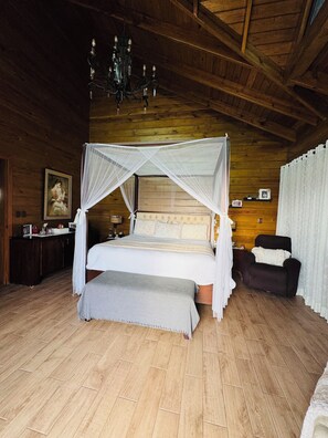 A wooden cabin-style bedroom with a four-poster bed, a chandelier, and a wooden ceiling. - Luxury Mountain Villa w Pool & Fire Pits (Jarabacoa)