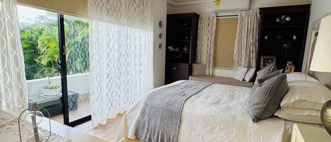 A bedroom with a bed, a ceiling fan, a window with curtains, a bedside table, and a nightstand.