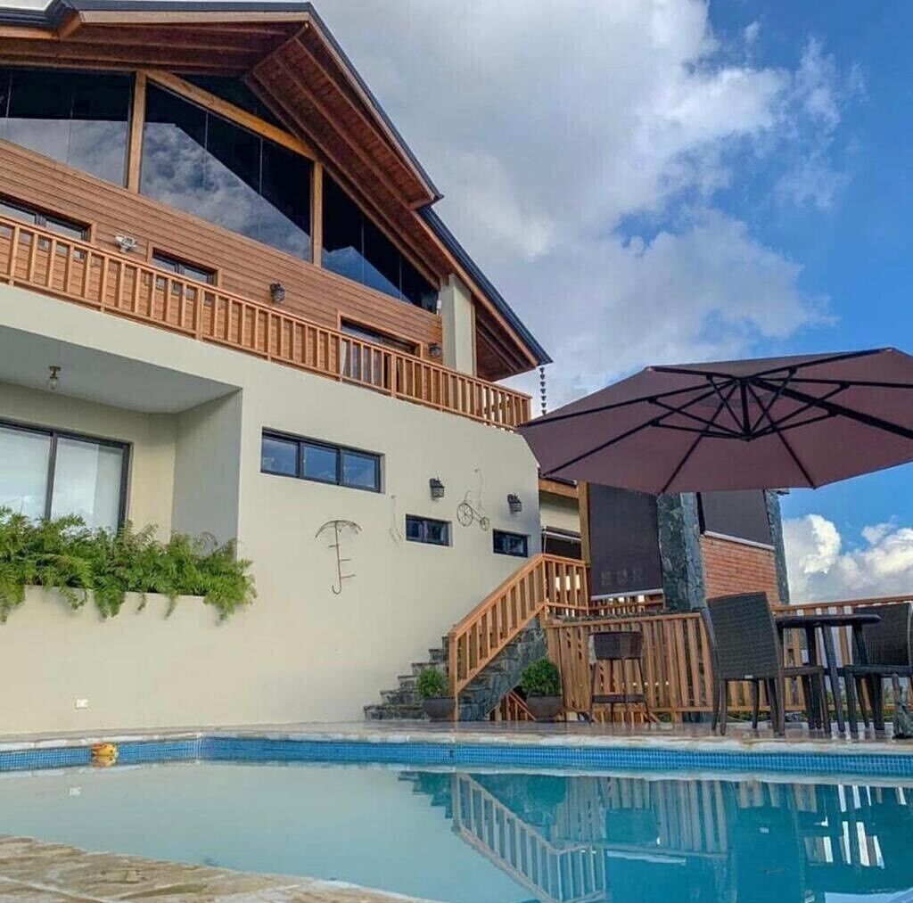 A modern building with a pool, wooden deck, and outdoor seating.