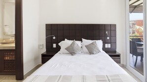 Ein Hotelzimmer mit einem großen Bett, einem dunklen Kopfteil, Nachttischlampen und Blick ins Freie.