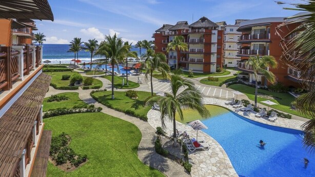 Ein Resort mit Swimmingpool, Palmen und Blick auf den Strand.