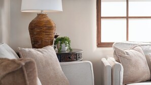 Ett rum med två soffor, en lampa, ett litet bord med en växt och ett fönster med utsikt.