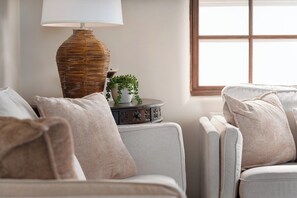 A room with two sofas, a lamp, a small table with a plant, and a window with a view. - Sagebrush Casita: 2bd/2.5bth Historic Property Close to Plaza (Santa Fe)