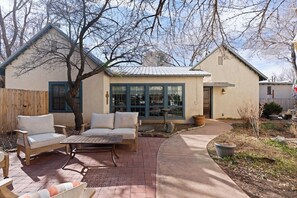 A house with a patio area, outdoor furniture, and a large window. - Sagebrush Casita: 2bd/2.5bth Historic Property Close to Plaza (Santa Fe)