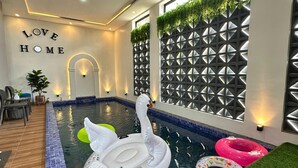 Una piscina interior con un flotador de cisne, flotadores de colores y un cartel que dice 'LOVE HOME'.