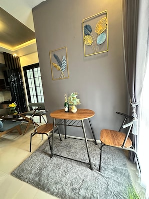 A dining area with a round table, two chairs, a vase with flowers, and framed artwork on the wall. - Athara Naya (Batu)