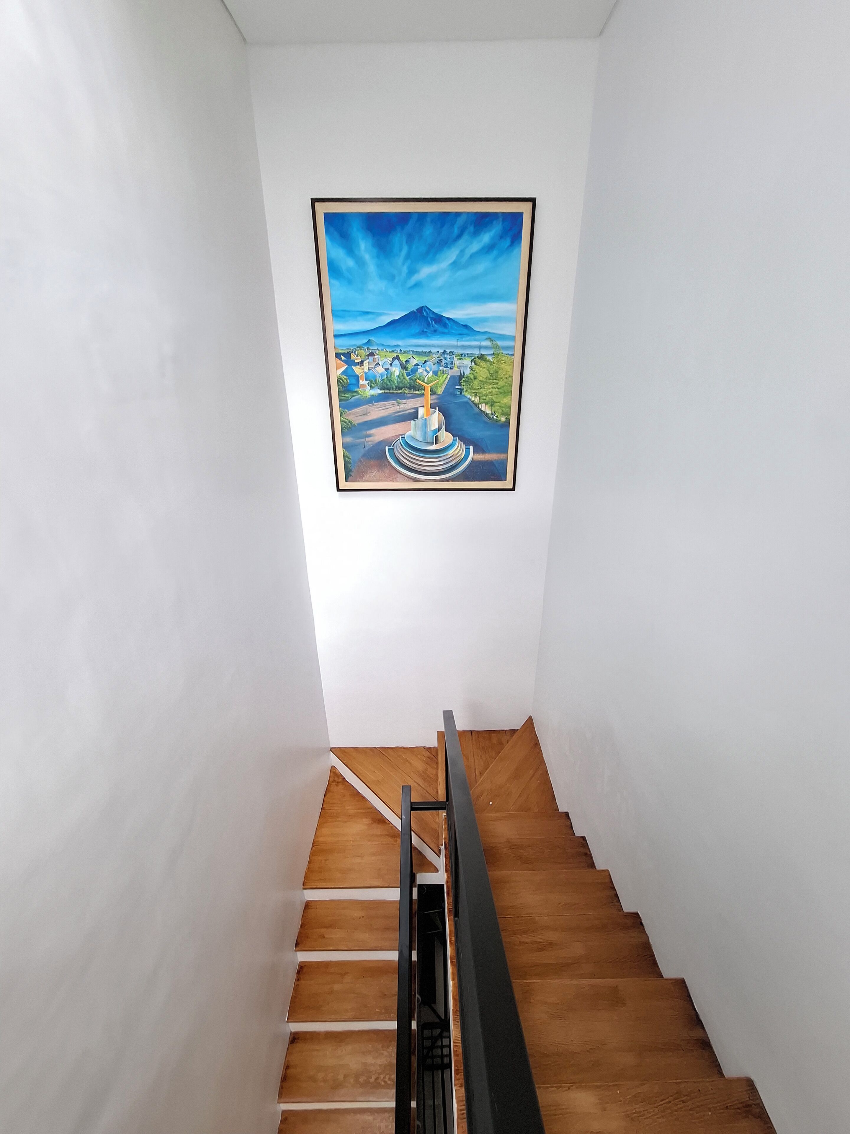 A staircase with wooden steps and a metal handrail, leading to a room with white walls.