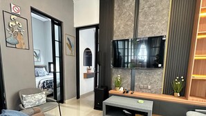 Una sala de estar moderna con un conjunto de sofá, un televisor de pantalla plana montado en la pared, un aparador de madera y una planta en maceta.