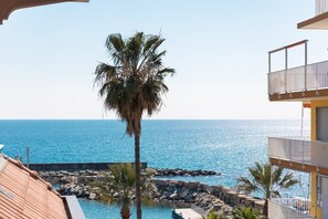 Blick auf einen Strand mit einer Palme, einem Pool und einem Gebäude mit Balkon.