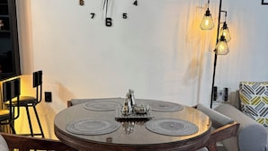 Un coin repas comprenant une table ronde, des chaises, une horloge murale et un lampadaire.