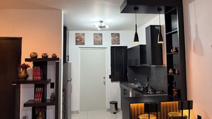 Une cuisine moderne dotée d’un îlot central, de meubles de couleur noire et de luminaires suspendus. On y trouve également un coin repas avec une table et des chaises.