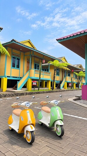 A row of colorful houses with a paved street in front. - Onsen Resort kaliurang (Pakem)