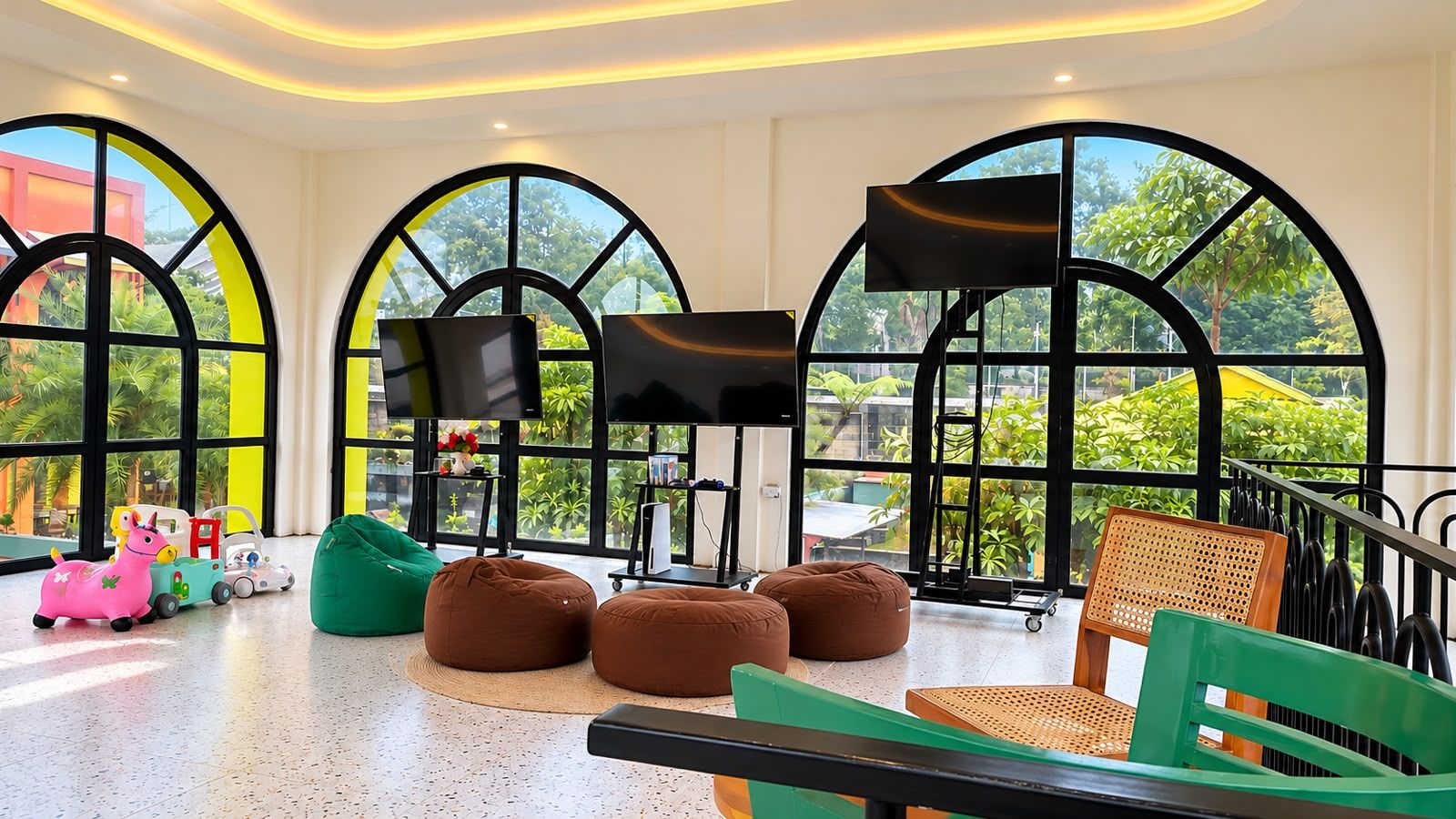 A spacious room with large windows, a flat-screen TV, bean bags, and a children's toy car.