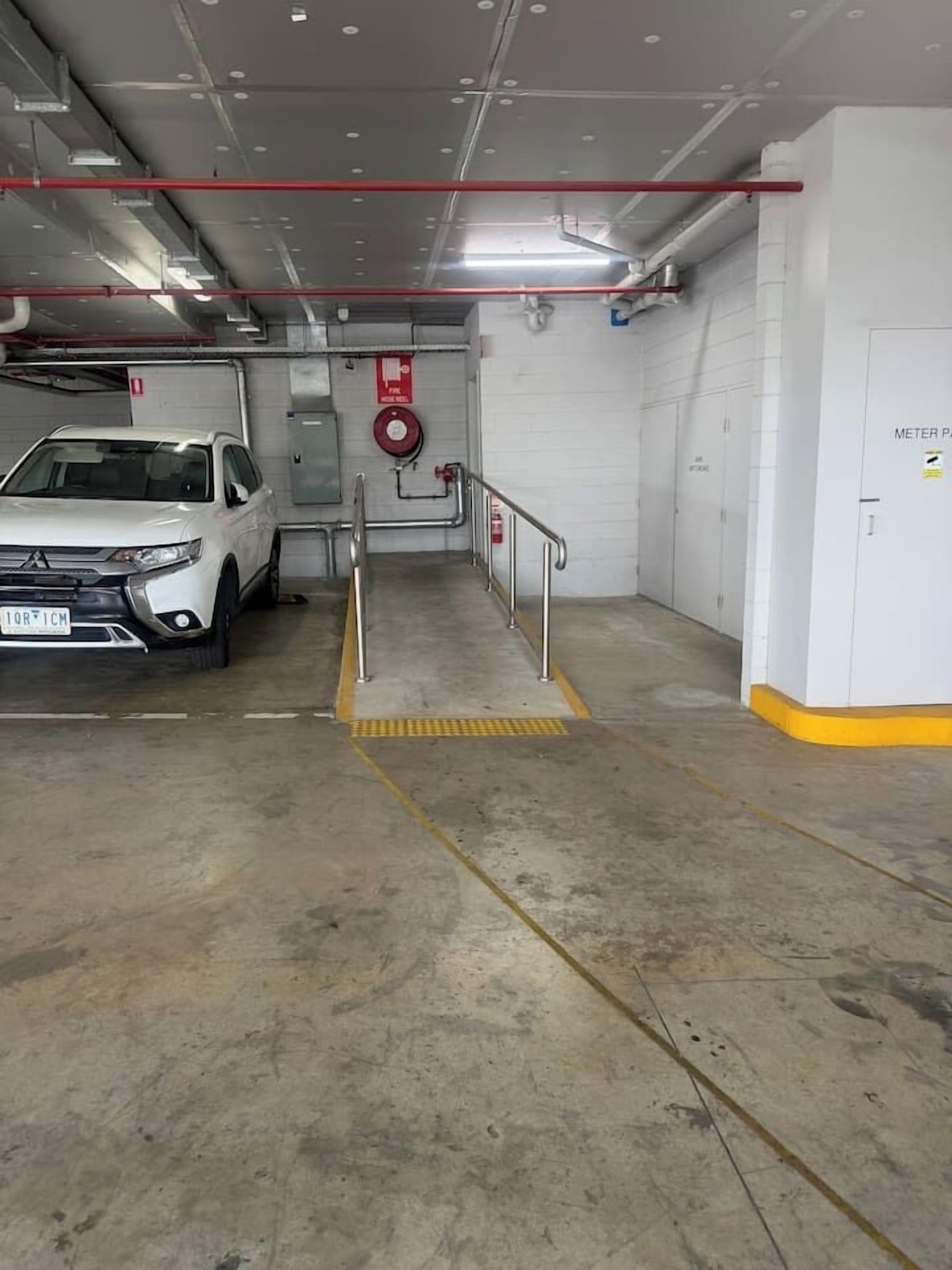 Eine Parkgarage mit Betonböden, Metallgeländern und einem Feuerlöscher an der Wand.