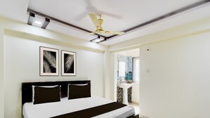 Un dormitorio con una cama, un ventilador de techo y dos diseños de hojas enmarcados en la pared.