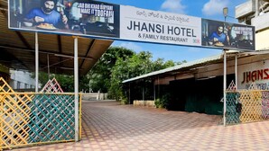 Entrada de hotel con un letrero que anuncia HOTEL JHANSI Y RESTAURANTE FAMILIAR.