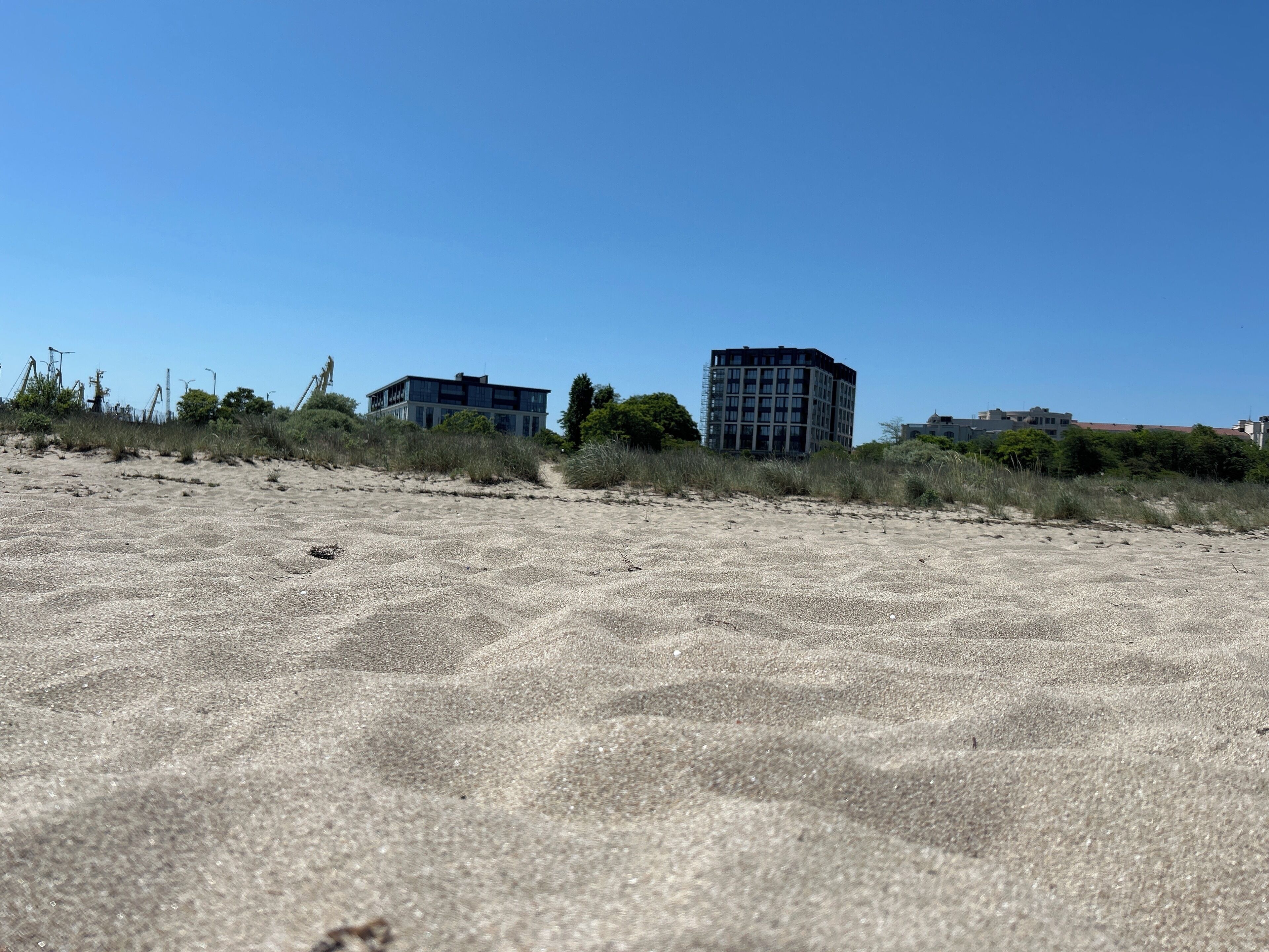 A sandy beach with buildings in the background.