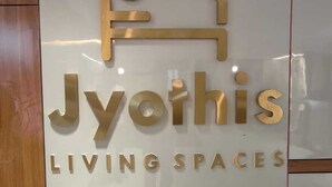 A sign with the text "Jyothis Living Spaces" and a stylized house graphic above it. - Jyothis living spaces (Bengaluru)