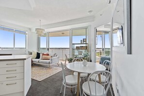 Une cuisine moderne avec des meubles blancs et un coin repas comprenant une table ronde et des chaises blanches.