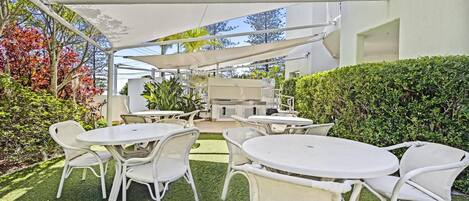 Un patio al aire libre con mobiliario de mimbre blanco y un espacio cubierto para sentarse.