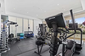 A gym with cardio equipment, weight machines, and dumbbells. - Bright 2 Bed Apartment with Ocean Views (Labrador)