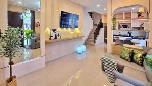 A modern living room with a TV, sofa, and a staircase leading to another level. - LeGacy By SanLiving - 3BR - PIK2 (Kosambi)