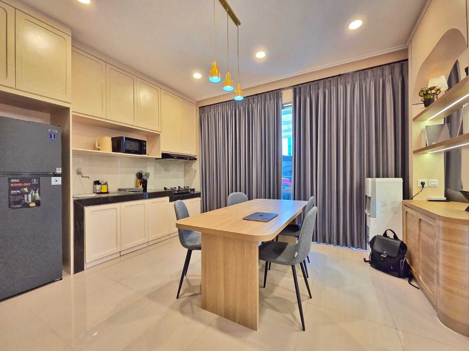 A modern kitchen with a dining area, including a wooden table, chairs, and a refrigerator.