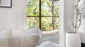 A room with a white sofa, a fluffy throw, and a large potted plant. - Conondale Lodge – Peaceful Country Escape (Conondale)