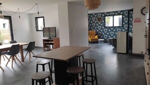 Eine moderne Küche mit Holztisch und Barhocker, einem Essbereich mit Stühlen, einem Fernseher und einer Wand mit Muster.