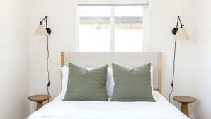 Un lit avec deux oreillers, une fenêtre et deux tables de chevet avec des lampes.