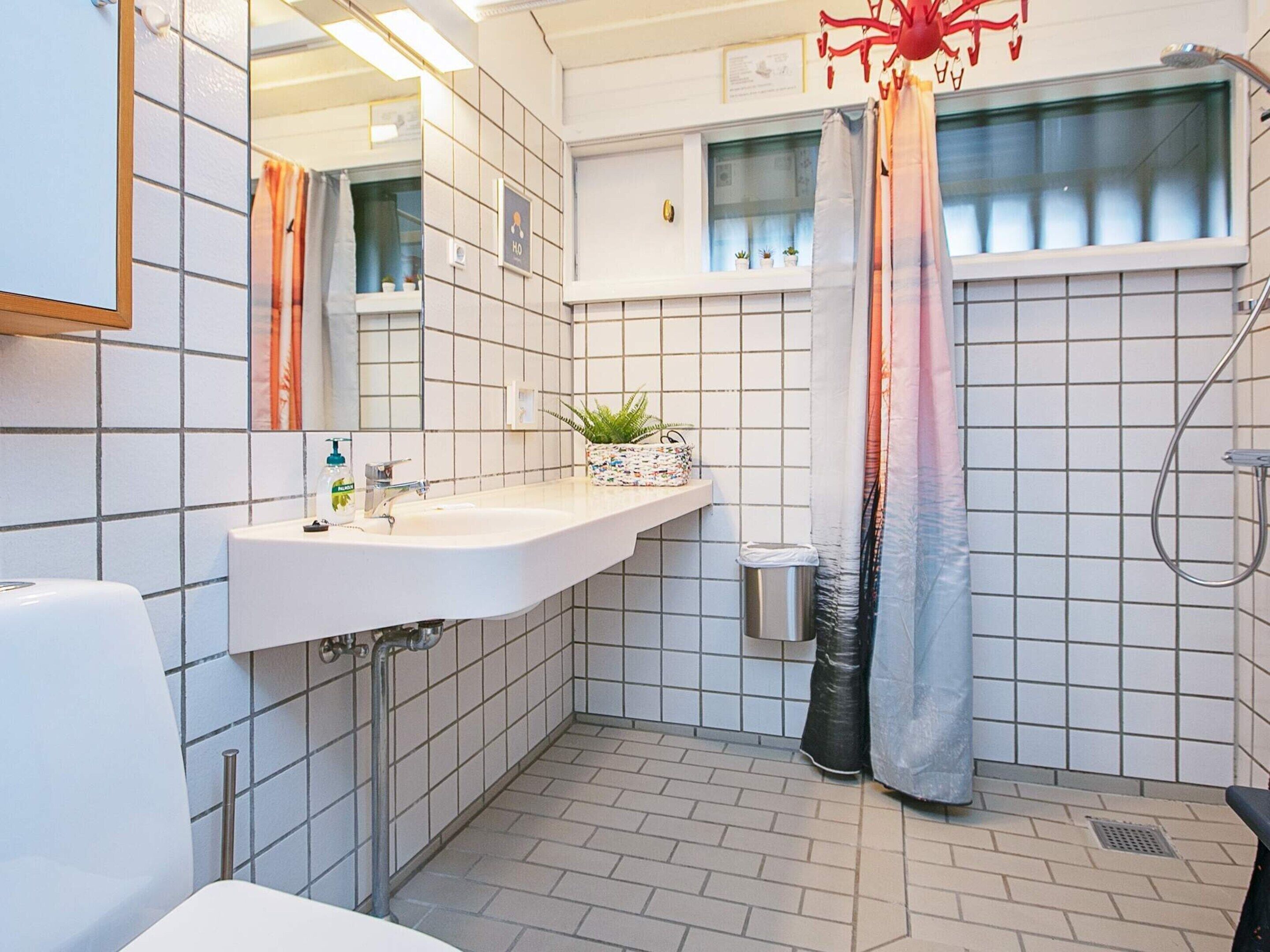 A modern bathroom with a white sink, mirror, and shower area.