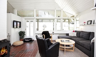 Una sala moderna con chimenea, un sofá, un sillón y una mesa de centro.