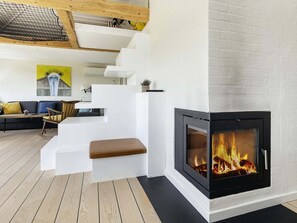Una sala de estar moderna con chimenea, suelo de madera y una escalera.