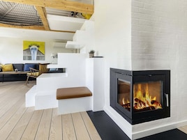 Una sala de estar moderna con chimenea, suelo de madera y una escalera.