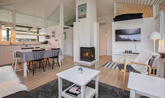Una sala de estar moderna con chimenea, comedor y cocina.