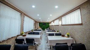 Ein Konferenzraum mit Tischen und Stühlen, einer grünen Wand und einer Wand mit Muster.