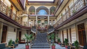 Eine prächtige Hotelhalle mit einer zentralen Treppe, aufwendigen Geländern und Topfpflanzen.
