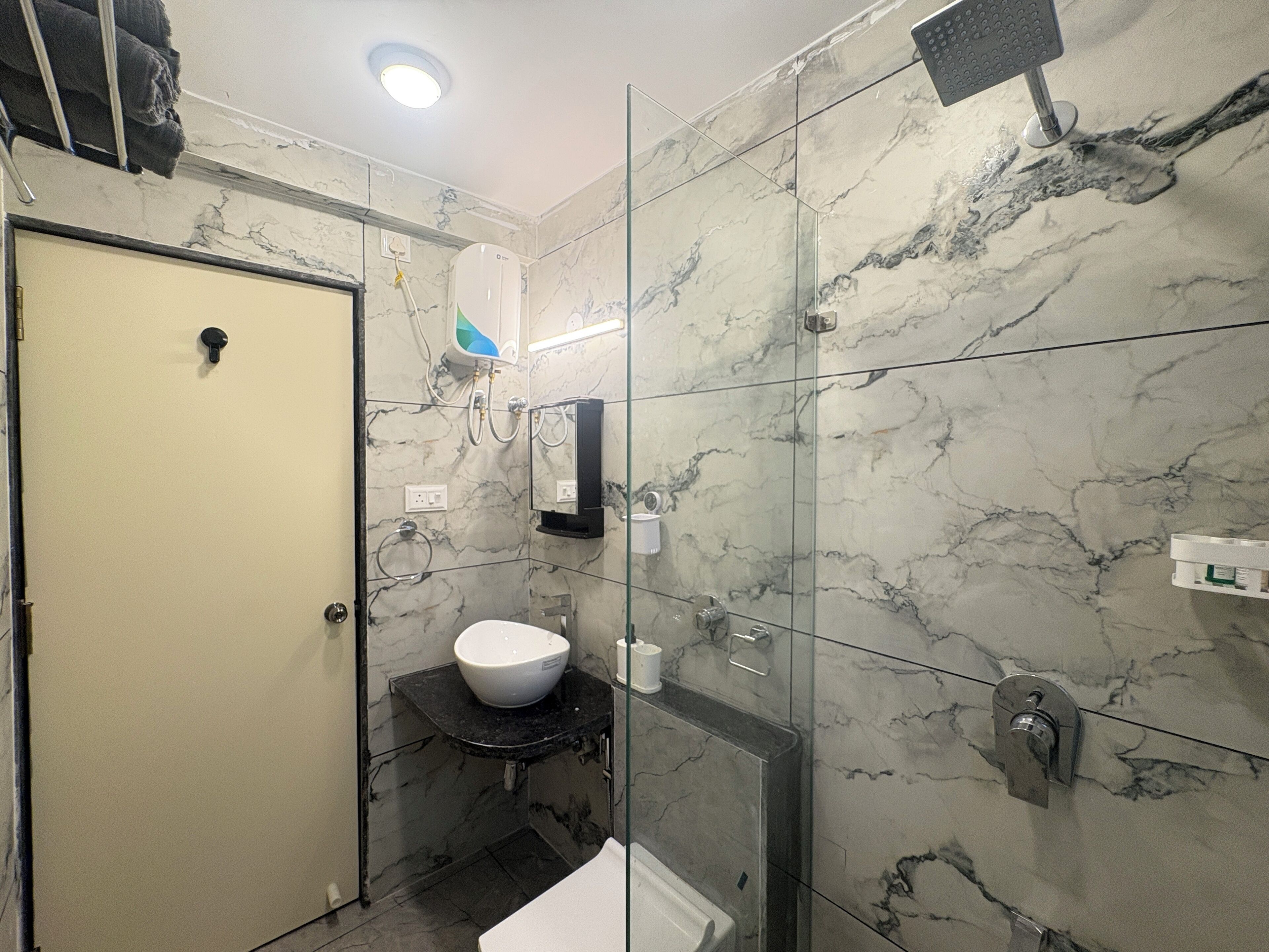 Une salle de bain avec un mur en marbre, des toilettes, un lavabo et une douche.