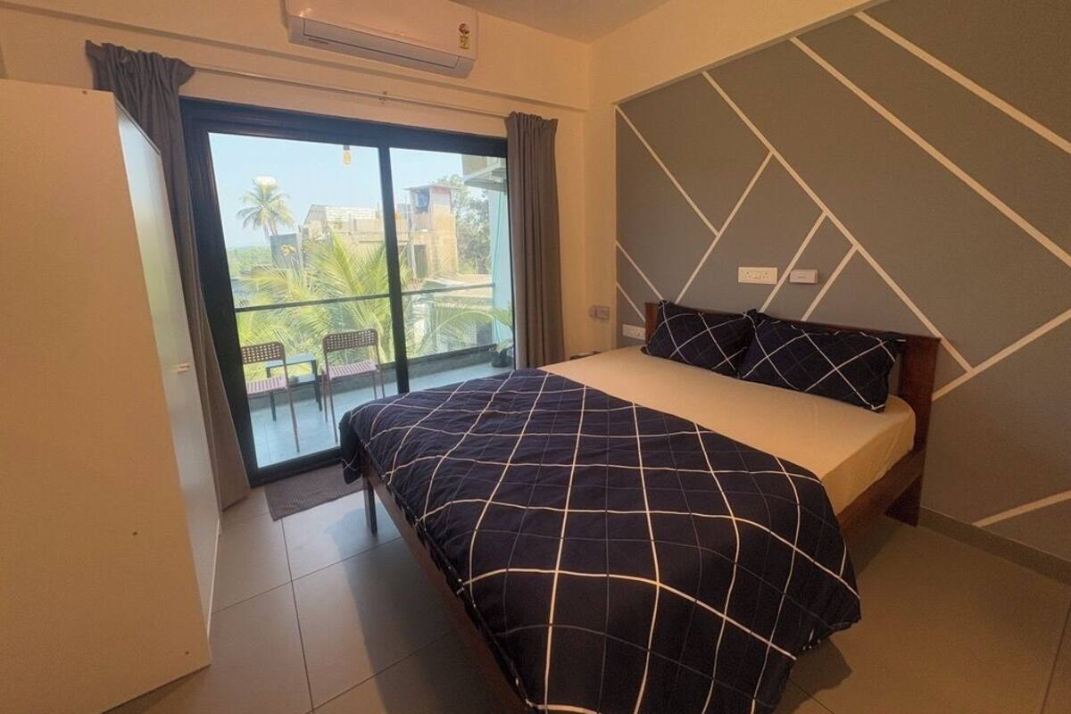 A bedroom with a bed, a view of the outdoors, and a modern wall design.