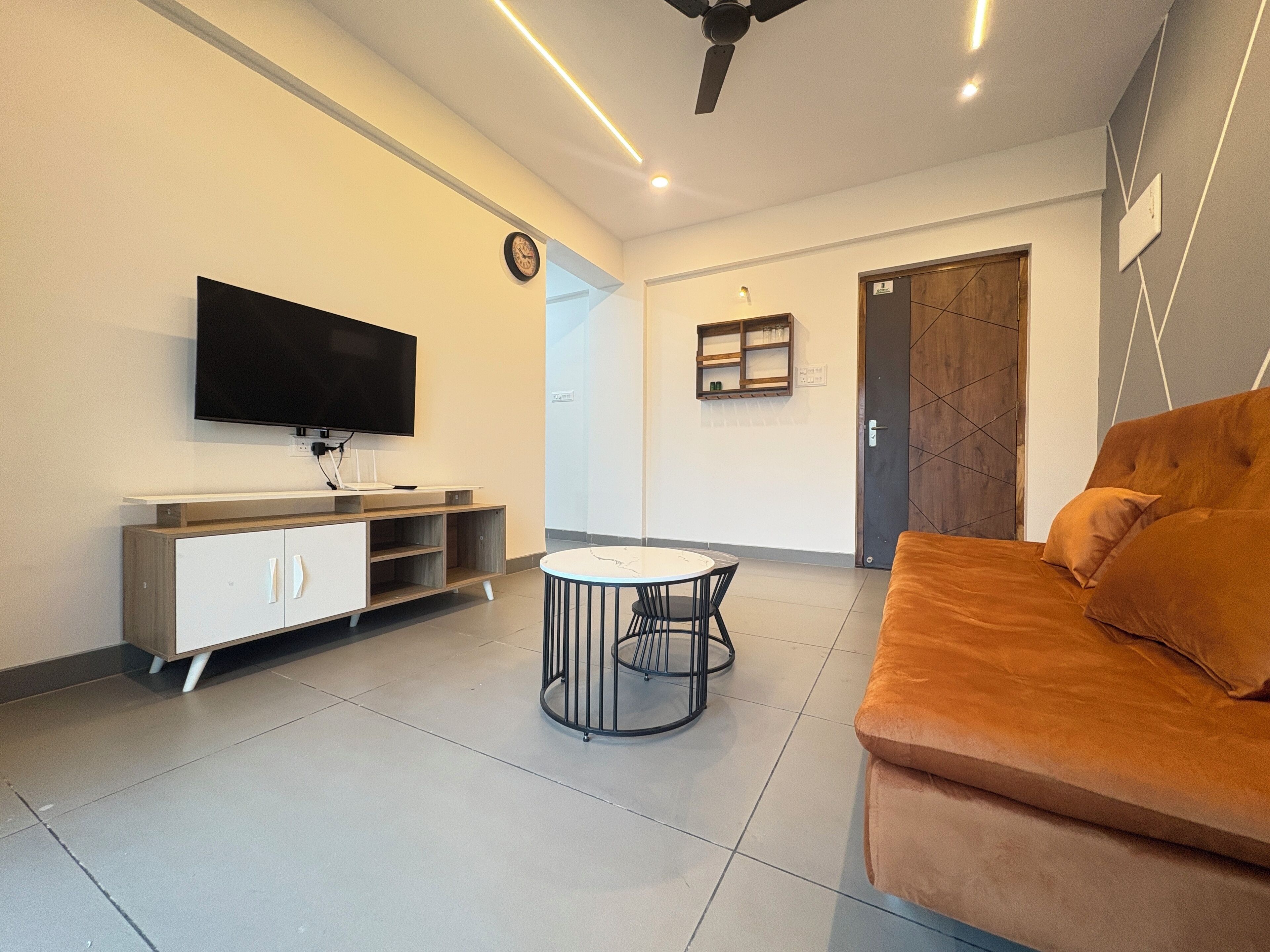Un salon moderne avec un téléviseur à écran plat, un canapé, une table basse et un meuble.