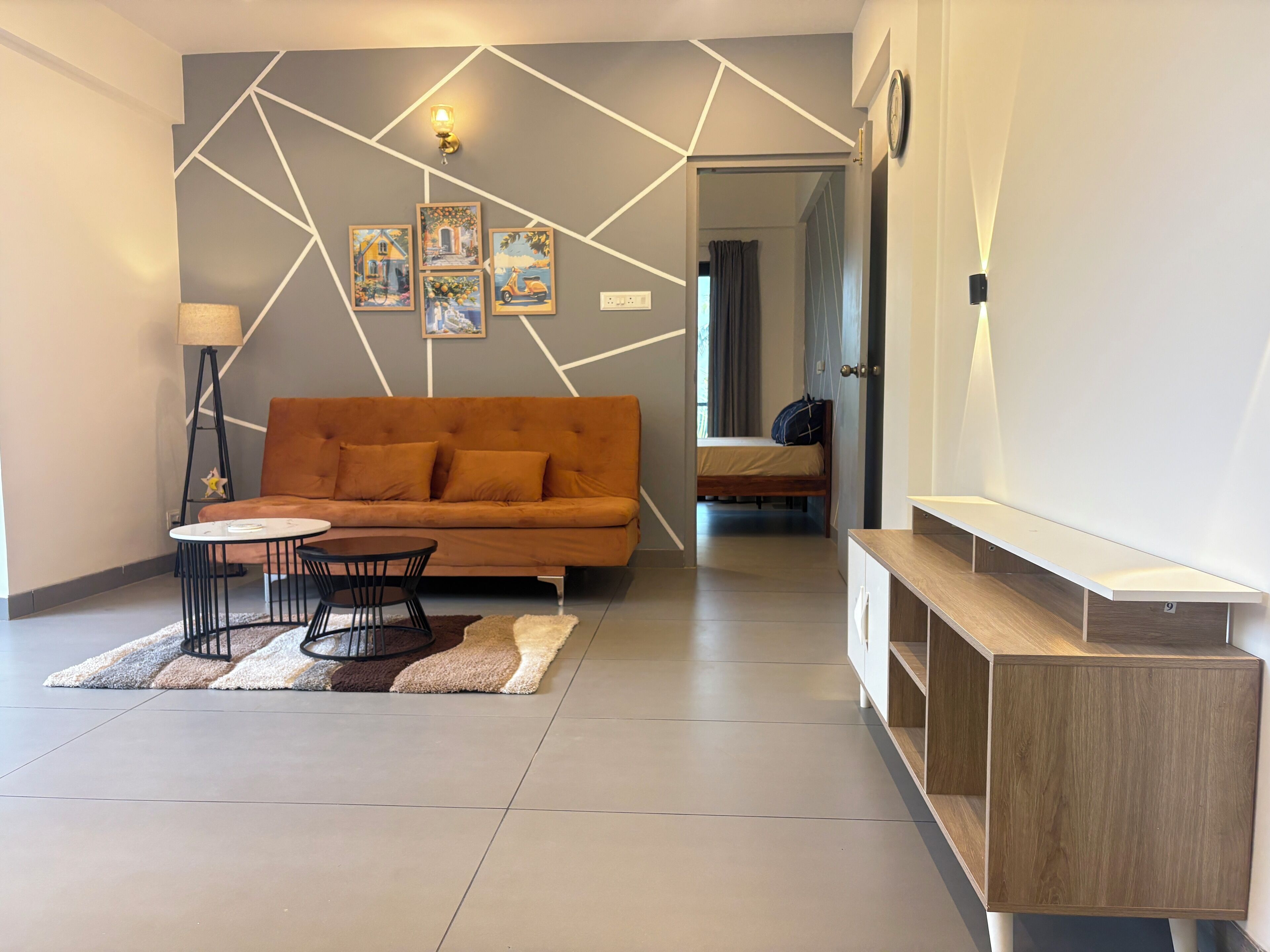 Una sala de estar moderna con un sofá, una mesa de centro y sillas. Hay cuadros en la pared y una lámpara.